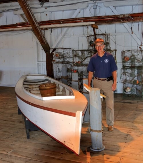  Chesapeake Bay Maritime Museum chief curator Pete Lesher stands beside an original Smith Island crab skiff in the museum’s small boat collection. Photo by Dick Cooper. 