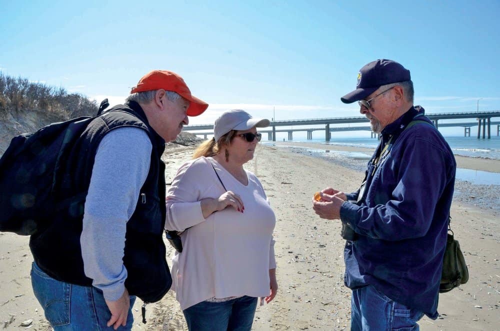   Jack Humphreys inspects a shell found by Mark and Esther Young of Virginia Beach during a hike on Fisherman Island. P hotos by Sarah Barban   